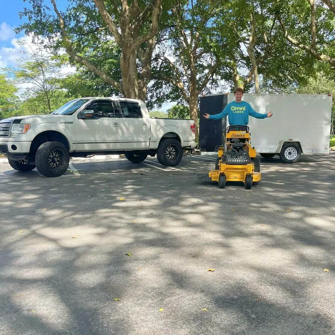 Person standing on a stand-on mower with a big smile, showcasing lawn care equipment, ready to tackle a fresh lawn care job.